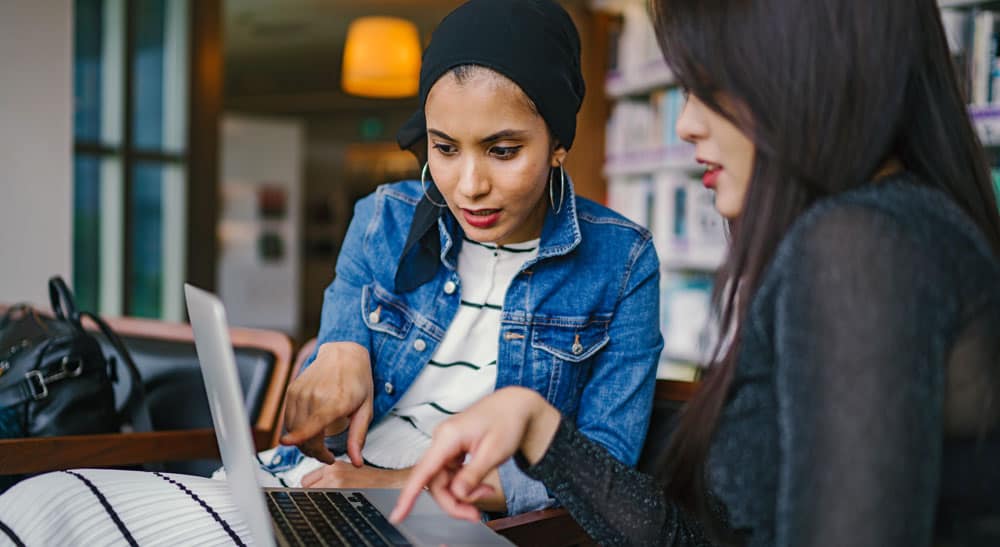 Female business owners exploring grants for women entrepreneurs on a laptop.