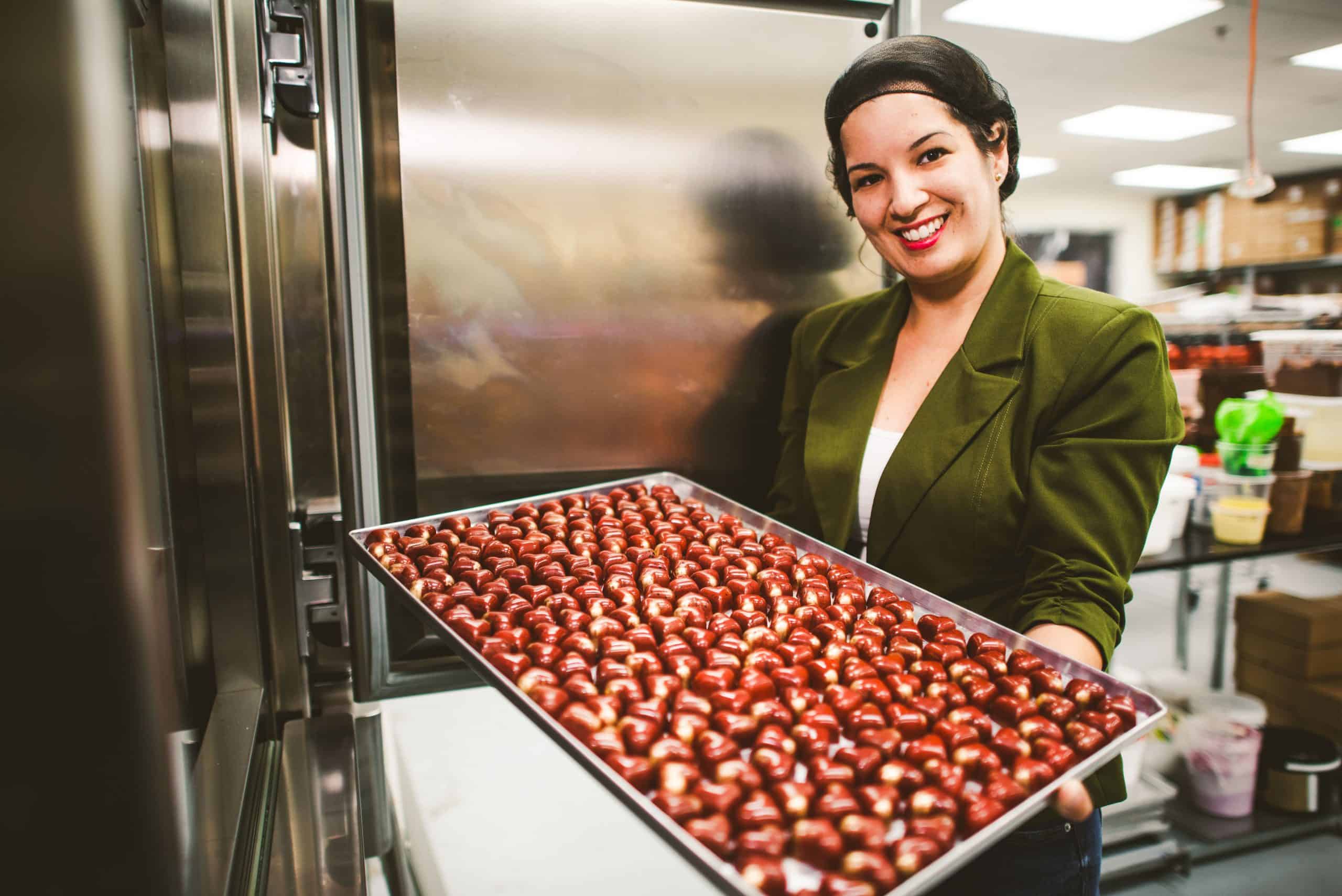 Smiling entrepreneur holding a tray of chocolates after securing a loan for small business.