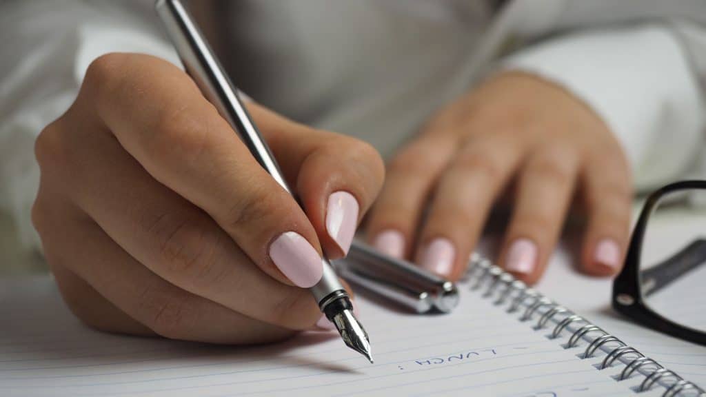 Close of a women's hands, writing notes pertaining to small business loans for women.
