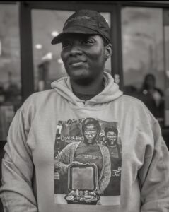 Black and white image of Kartisha Henry wearing a wing suite hoodie and baseball hat