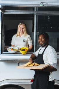 Alison and Conroy, experts in how to start a food truck, stand outside their food truck, JA Patty