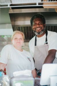 Alison and Conroy, experts in how to start a food truck, stand in their food truck, JA Patty