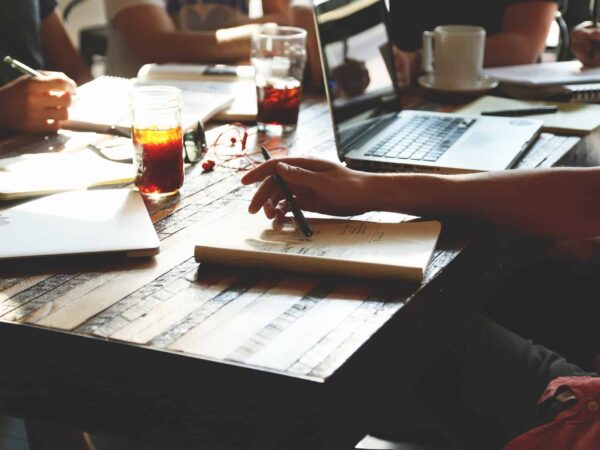 People sitting around a table covered in papers, laptops, and coffee cups
