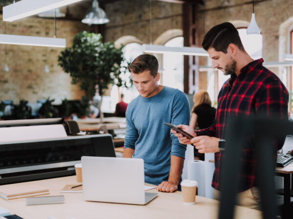 Serious smart young colleagues standing in the office while working together on design project