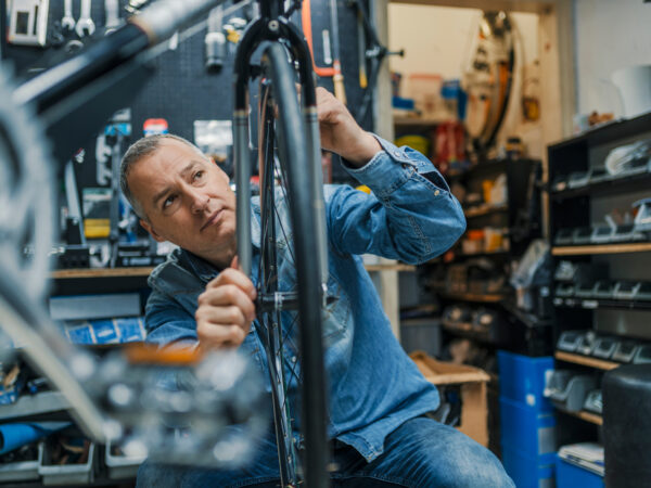 Bicycle mechanic carrying a bike in workshop