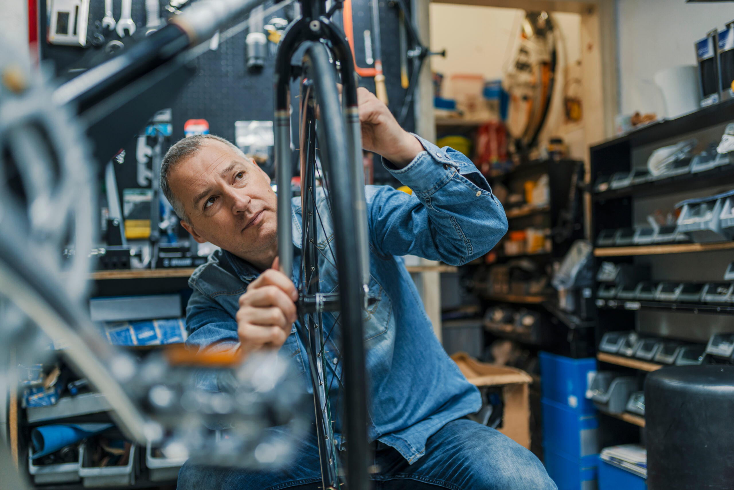 Bicycle mechanic carrying a bike in workshop