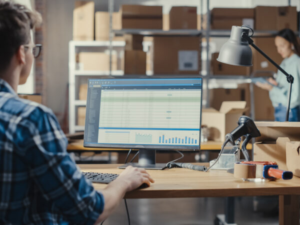 Young Man Using Desktop Computer with a Dashboard and Orders Information Display.