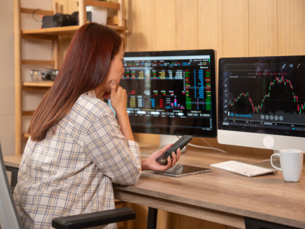 Young woman doing cryptocurrency business trading on her computer at home at night