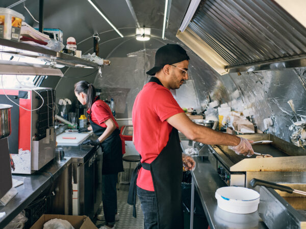 Gloved man in uniform putting fast food on electric stove