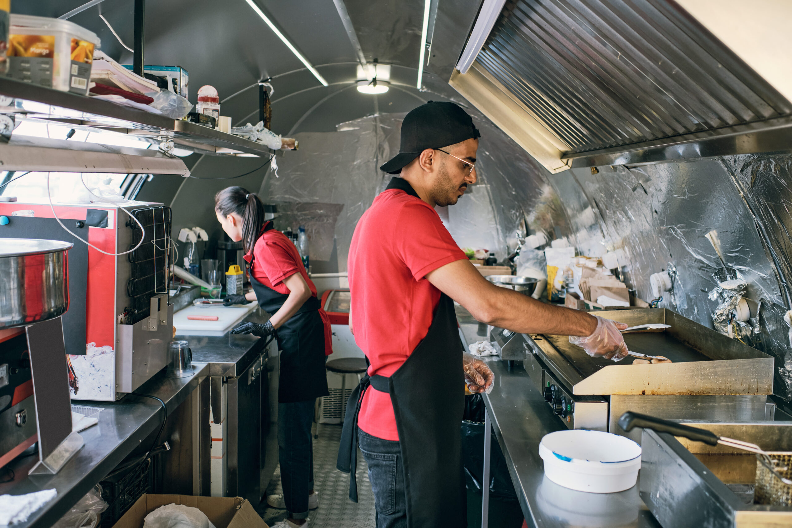 Gloved man in uniform putting fast food on electric stove